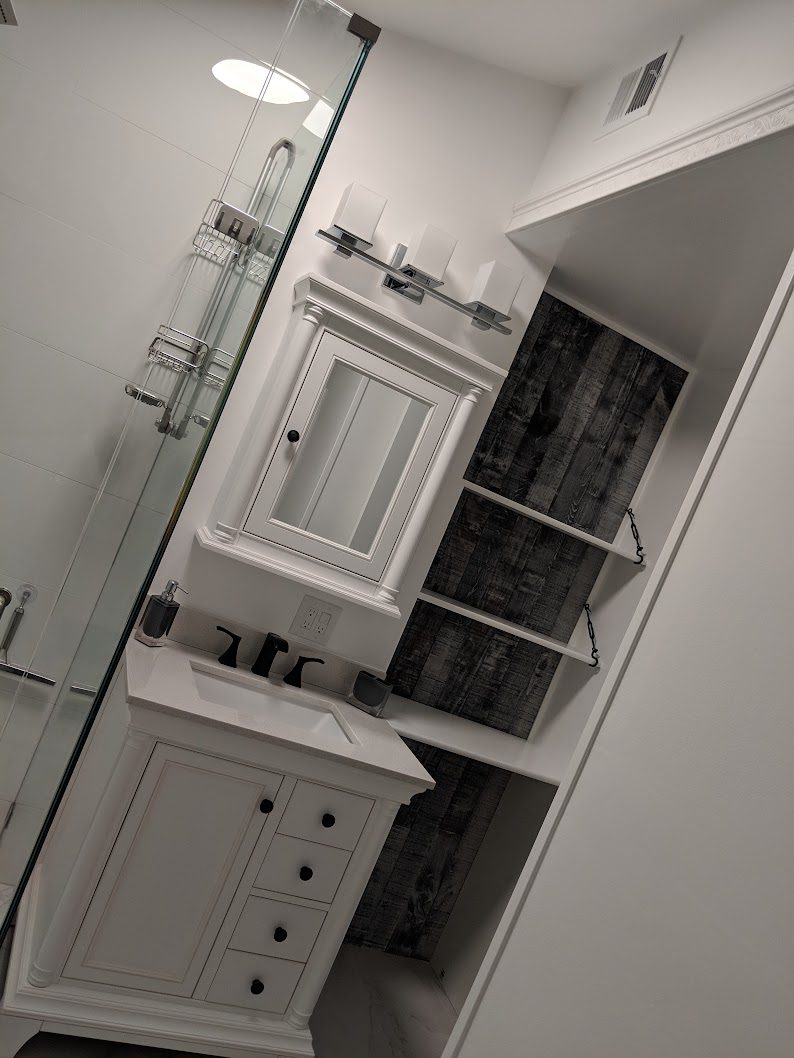 Finished vanity with mirrored cabinet, sconces and glass shower