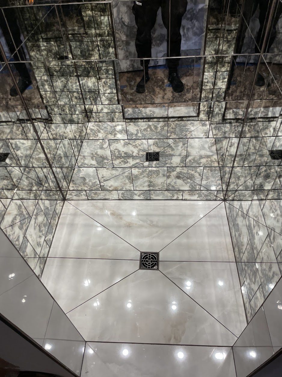 Finished walk-in shower with book-matched marble and mirrored walls