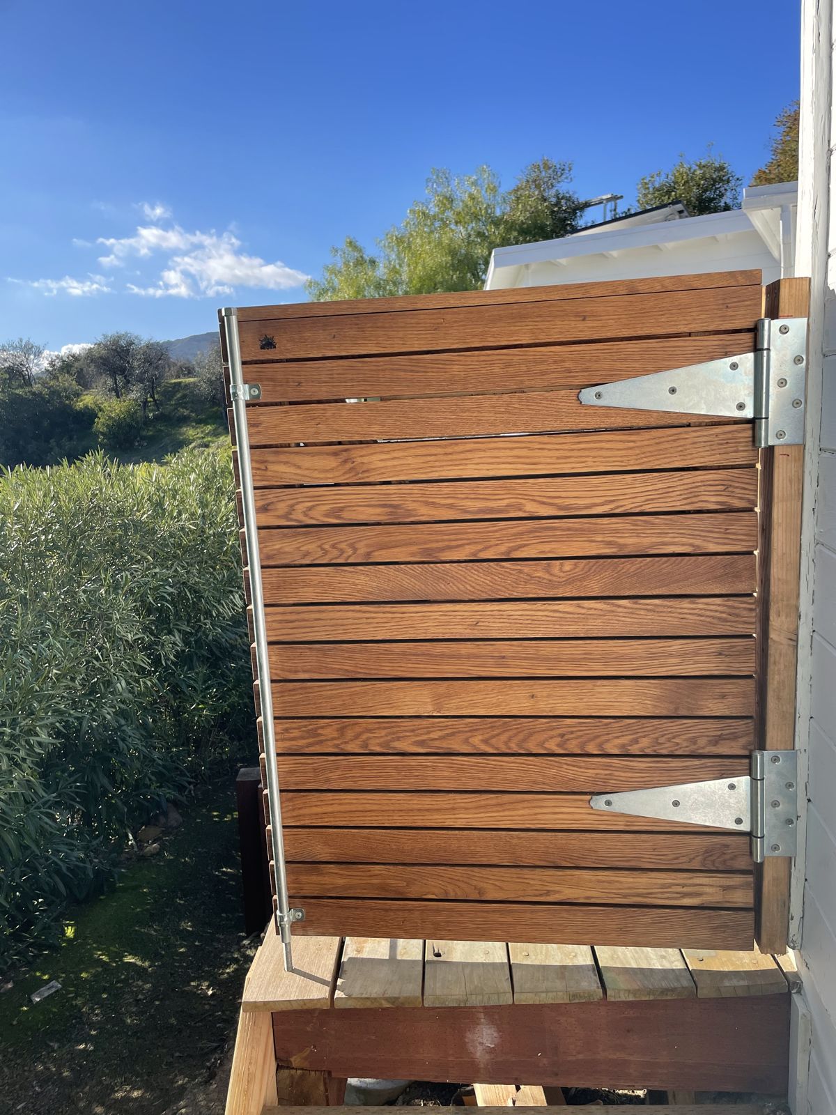 Hinged white oak gate open beside the deck
