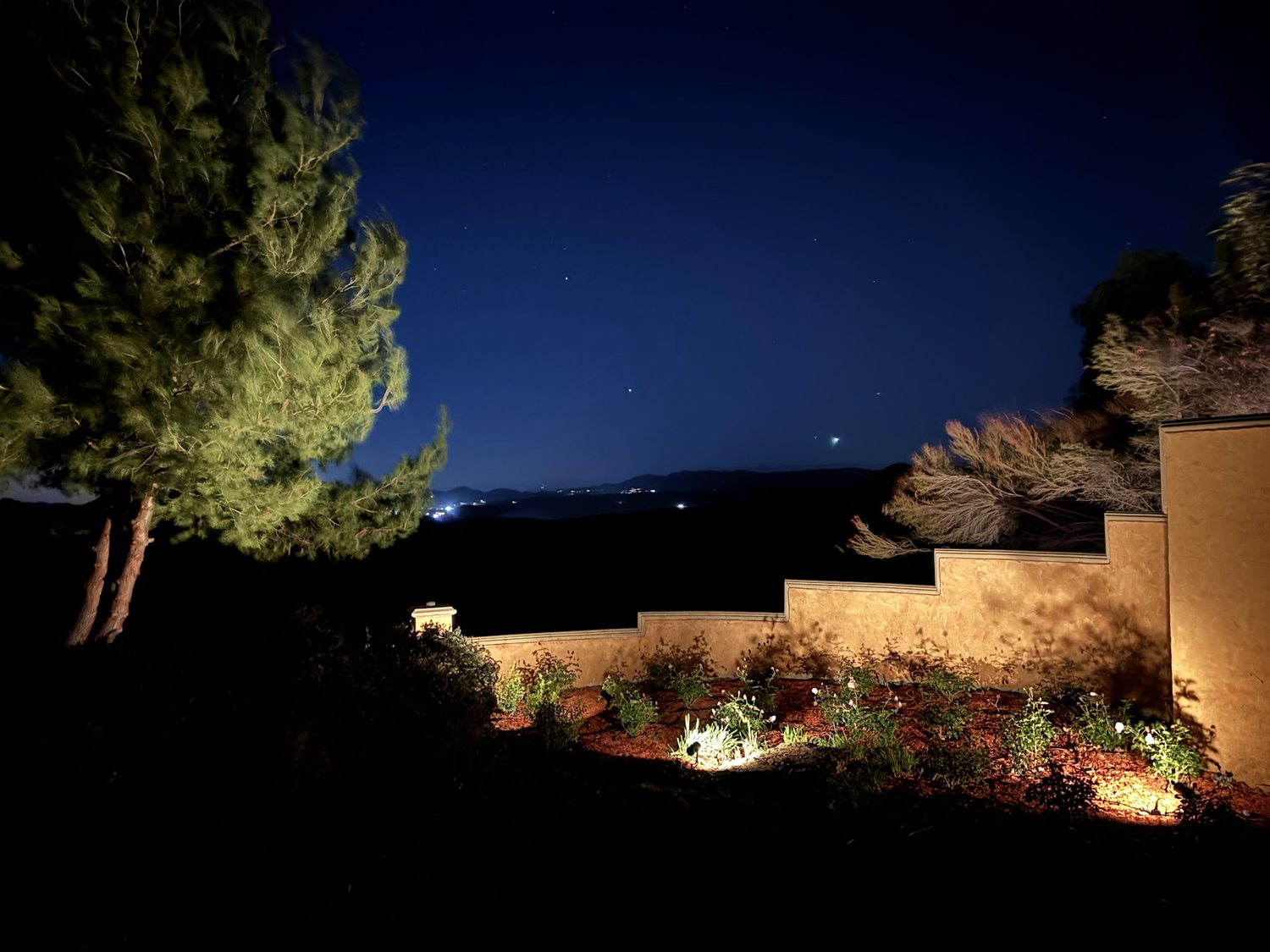 Lit terrace wall and planting above the hillside view