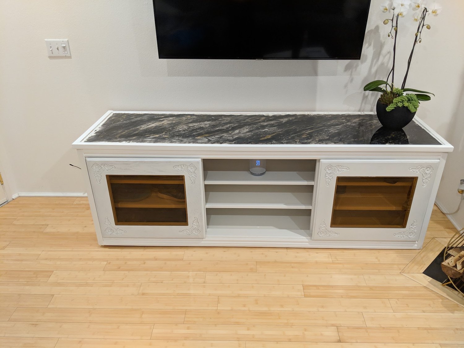 The finished white media console with glass-fronted cabinets beneath a wall-mounted TV